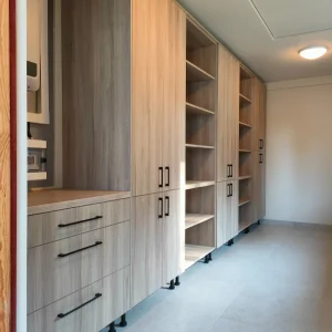 Funkcjonalne meble na wymiar do pomieszczenia gospodarczego z wysokimi szafami, otwartymi półkami i szuf